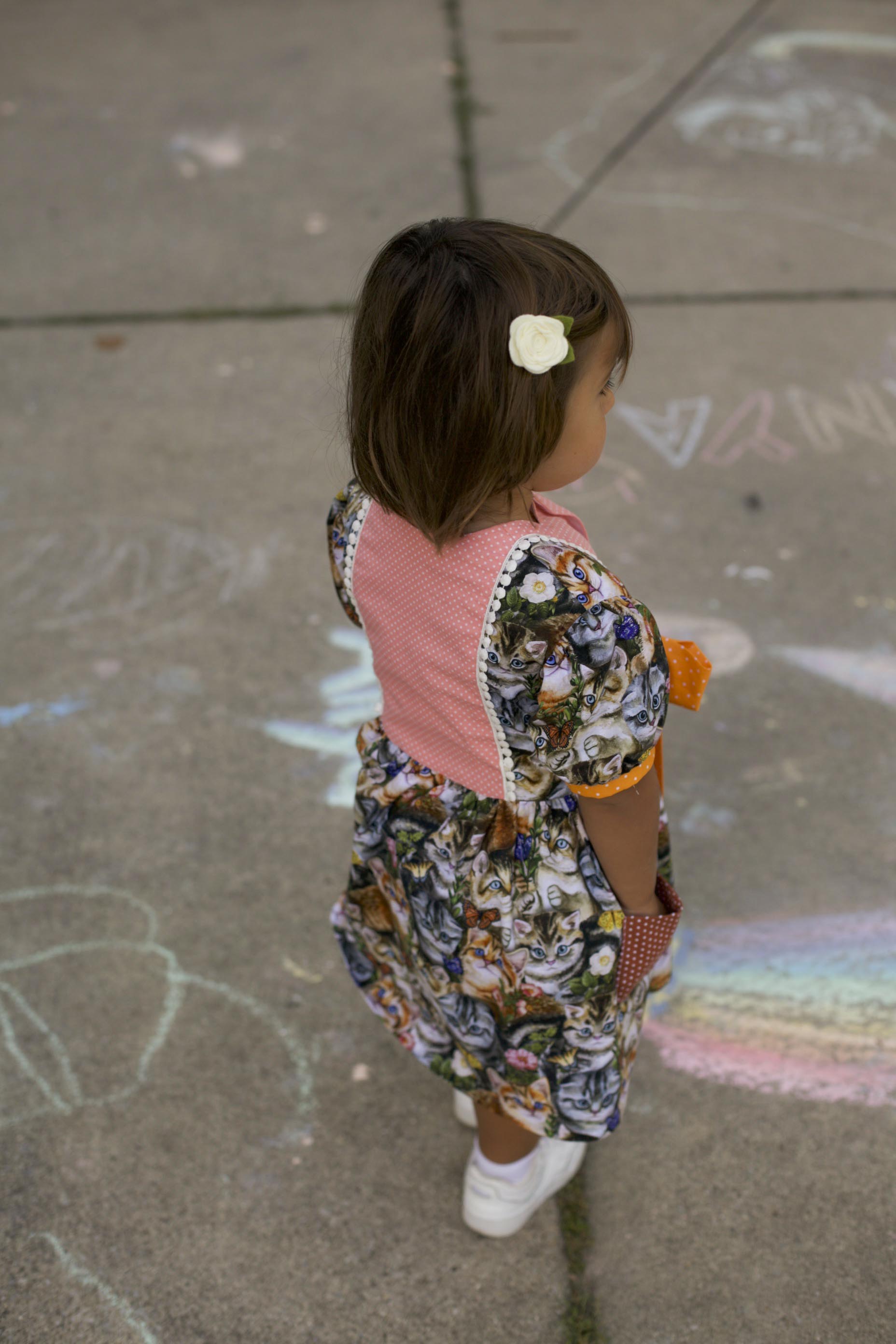 Little girl wearing handmade kitty cat cotton dress with polka-dot bow and pockets — perfect for school or play”